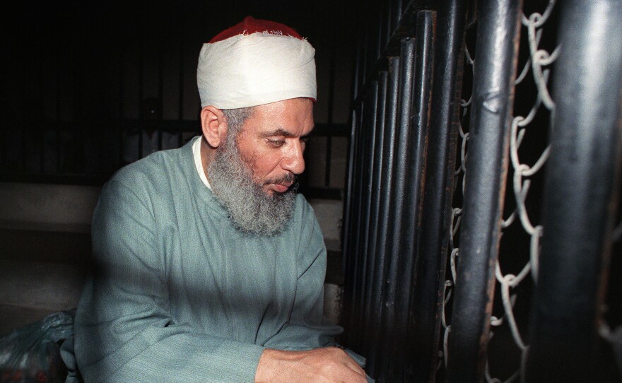 Blind Sheikh Omar Abdel Rahman sits and prays inside an iron cage at the opening of a court session in Cairo in 1989.