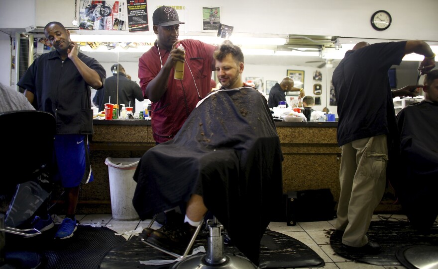 Barber Stan Norwood (center) puts the finishing touches on a cut and style to Mike Fox's hair at the Dennis Barber Shop in Freret, a transitional neighborhood in central New Orleans.