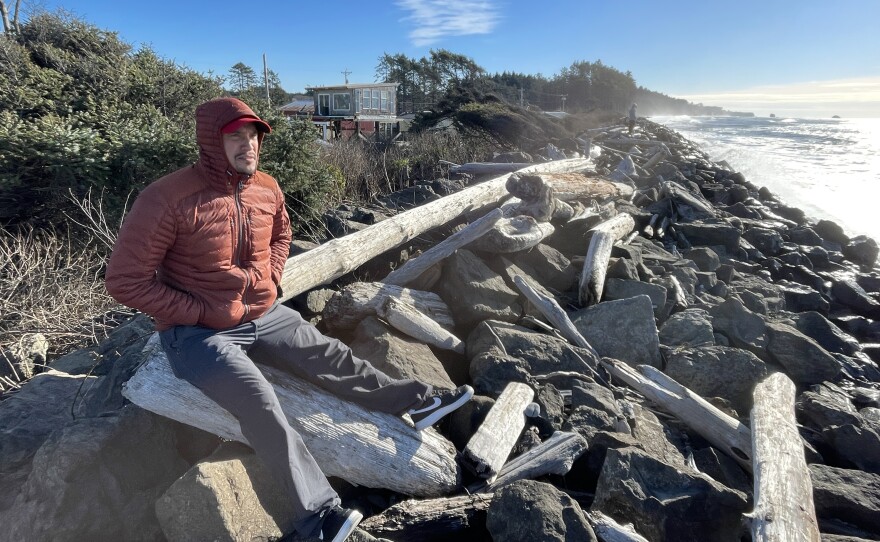 Ryan Hendricks, who is a member of the Quinault Tribal Council, sits on a driftwood log on the Taholah, Wash., sea wall. The coastal tribe is working to move its villages away from the rising waters of the Pacific Ocean and its tsunamis.
