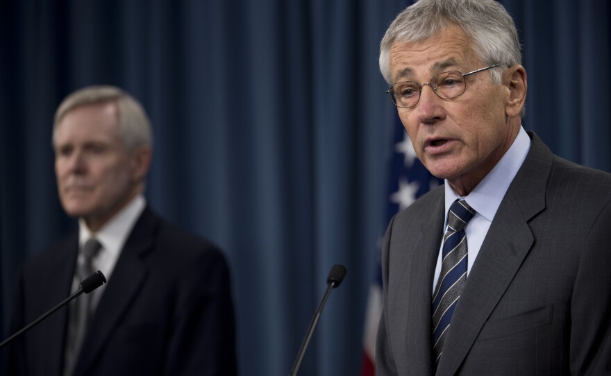 Defense Secretary Chuck Hagel delivers remarks as Navy Secretary Ray Mabus looks on during a briefing at the Pentagon, March 18, 2014. 