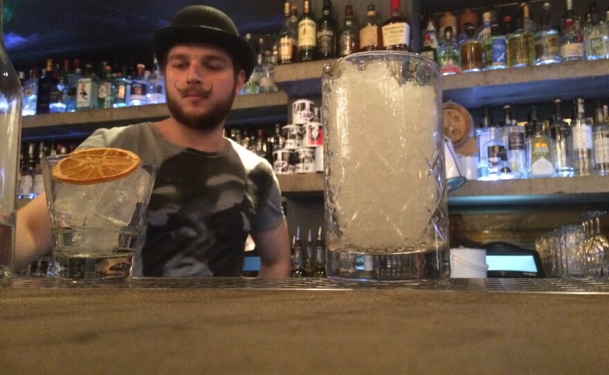 A bartender at Graphic works on drinks for NPR reporter Ari Shapiro and producer Rich Preston.