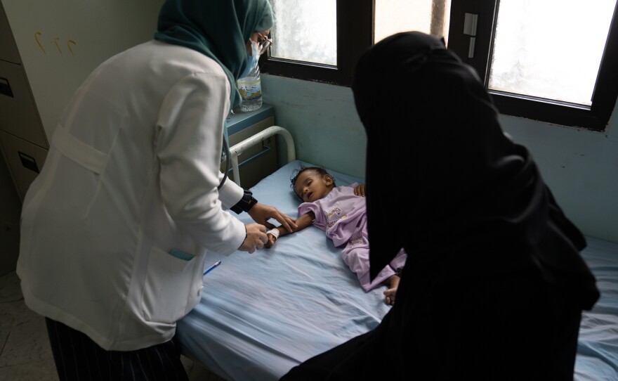 A nutritionist (left) checks a 9-month-old girl who is suffering from dehydration at Al-Thawra hospital in Taiz, Yemen. The girl's condition has improved since she arrived at the clinic.