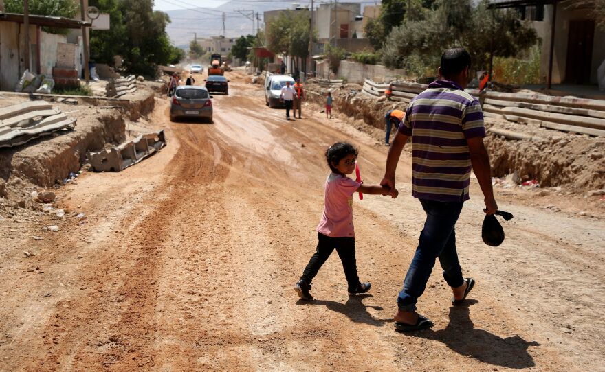 A father and his daughter cross a street under renovations as part of a U.S. aid grant in the village of al-Badhan, north of Nablus in Israeli occupied West Bank in August 2018.