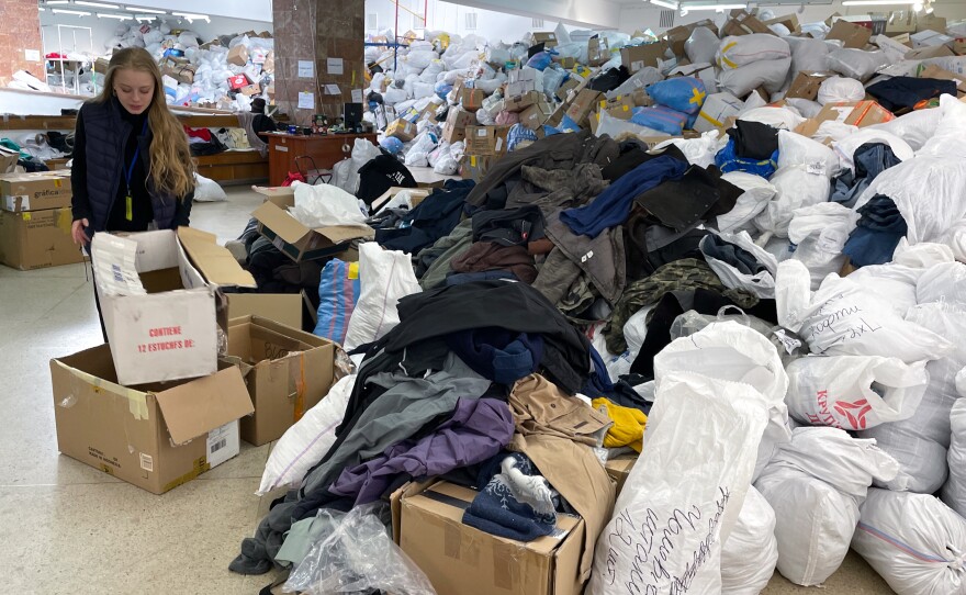 Nastia Stefanovich, a volunteer at the distribution center in Lviv for goods donated for Ukrainians in need, points out the piles of clothes that have been arriving.