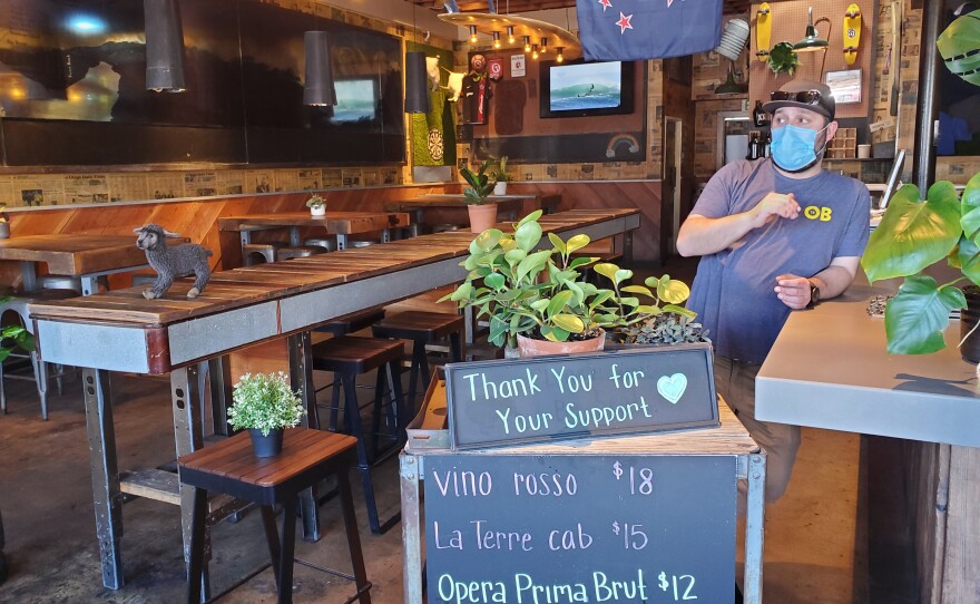 A manager at Raglan Public House in Ocean Beach helps prepare the restaurant for dine-in customers, May 18, 2020.