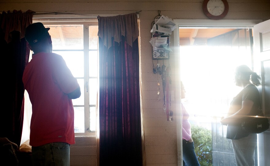 Francisco Duran scans the street from his window before stepping out to drive his mother to English class. He had just warned his friends on Facebook that a sherriff's deputy was a few blocks from his home on Phoenix's west side.