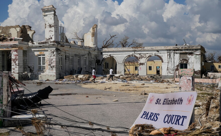 People walk past damage from Hurricane Melissa in Black River, Jamaica on Thursday, Oct. 30, 2025. Federal forecasters predict 8 to 14 named storms, including tropical storms and hurricanes, will form in the Atlantic in 2026.