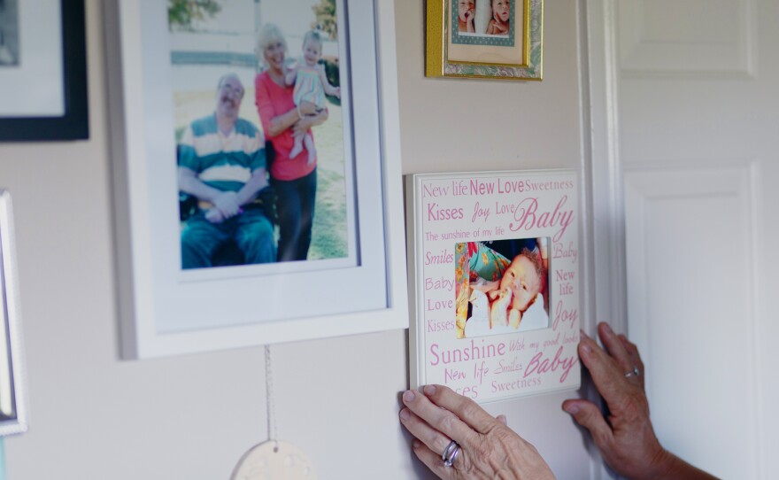 Luann Thibodeau adjusts a family photo in her home. Before the coronavirus outbreak, she would take her husband to church on Sunday and to the movies. They'd go out for fast food. But she says his anxiety has increased since the lockdown began.