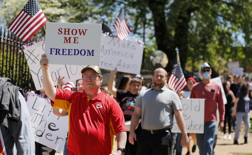 People walk past the governor's mansion to protest stay-at-home orders put into place due to the COVID-19 outbreak Tuesday in Jefferson City, Mo.