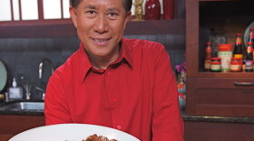 International chef and television host Martin Yan in the kitchen holding a plate of food. 