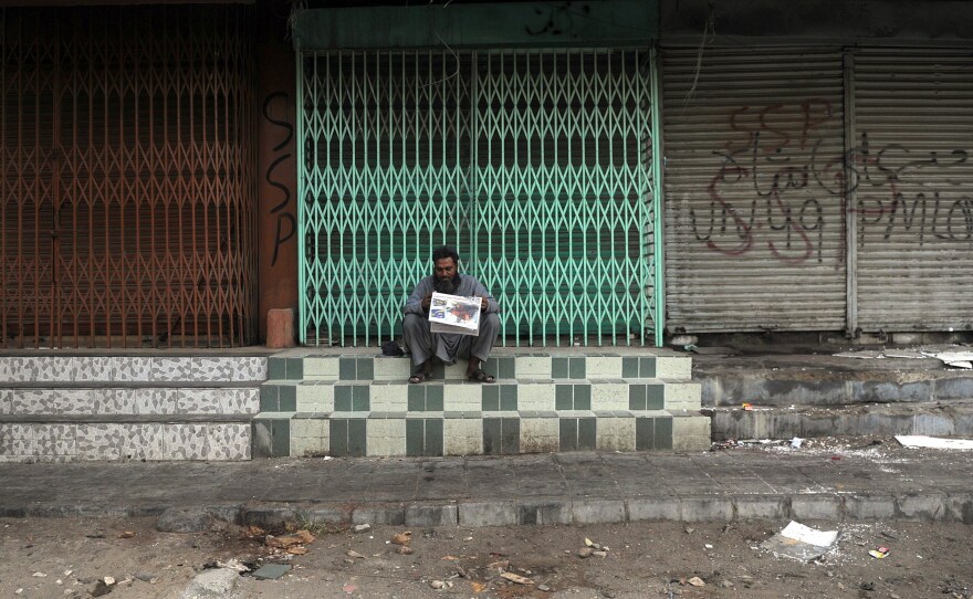 A Pakistani man reads a newspaper at a closed market in Karachi on Wednesday following the arrest of Altaf Hussain. For more than two decades, Hussain has wielded control over his party — and by extension, parts of the city — from half a world away in London.