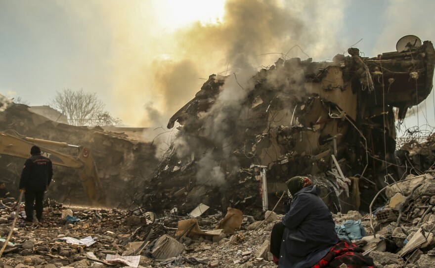 People stand by a collapsed building in Kahramanmaras, in southern Turkey, on Sunday.