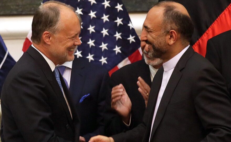 Afghan National Security Advisor Hanif Atmar (right) and U.S. Ambassador to Afghanistan James Cunningham exchange documents after signing the bilateral security agreement, with Afghan President Ashraf Ghani (rear, left) and Chief Executive Abdullah Abdullah in the background.