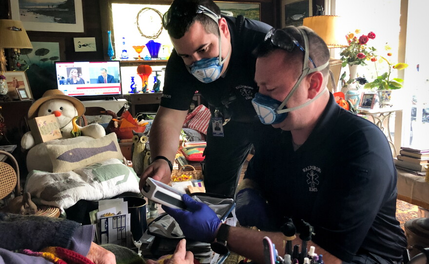 In between answering 911 calls, Jerrad Dinsmore (left) and Kevin LeCaptain perform a wellness check at the home of a woman in her nineties. The ambulance team in the small town of Waldoboro, Maine was already short-staffed. Then a team member quit recently, after the state mandated all health care workers get the COVID-19 vaccine.
