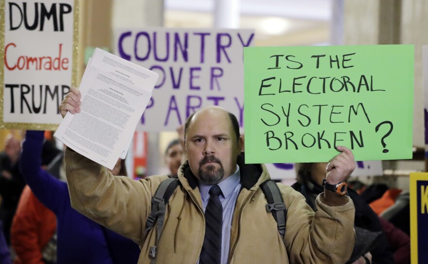 Brock Ervin holds a sign outside the Indiana House chamber before the 11 representatives of the Electoral College gathered on Dec. 19, 2016, in Indianapolis. The U.S. Supreme Court has agreed to hear two cases challenging state attempts to penalize Electoral College delegates who fail to vote for the presidential candidate they were pledged to support.