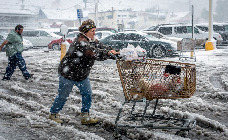As snow fell in Rapid City, S.D., Friday Brenda Nolting took groceries to her car. An early snow storm swept through Wyoming and western South Dakota, dropping more than two fee of snow in some areas.