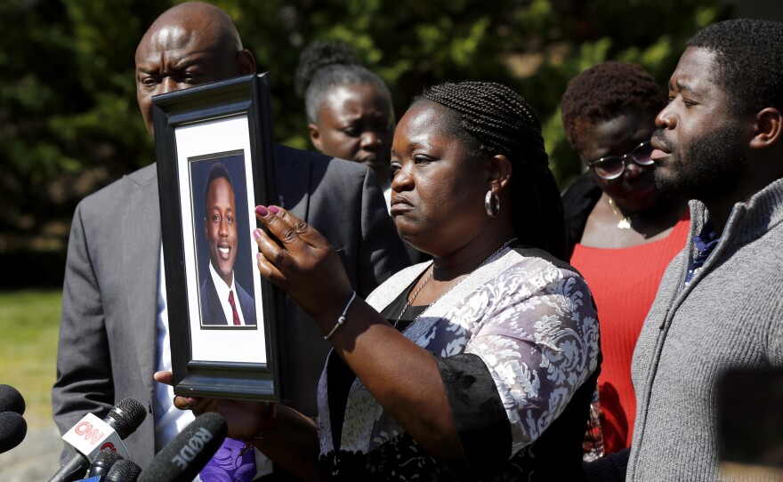Caroline Ouko holds a portrait of her son, Irvo Otieno, as attorney Ben Crump (left) and her older son, Leon Ochieng (right) look on at the Dinwiddie Courthouse in Dinwiddie, Va., on Thursday.