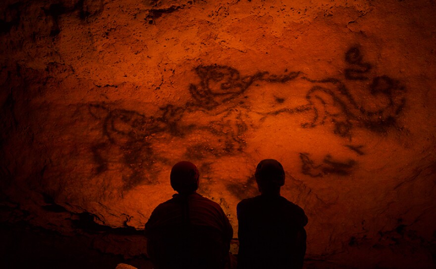 Steve and Guillermo studying a jaguar illustration on the cave wall. Mexico.