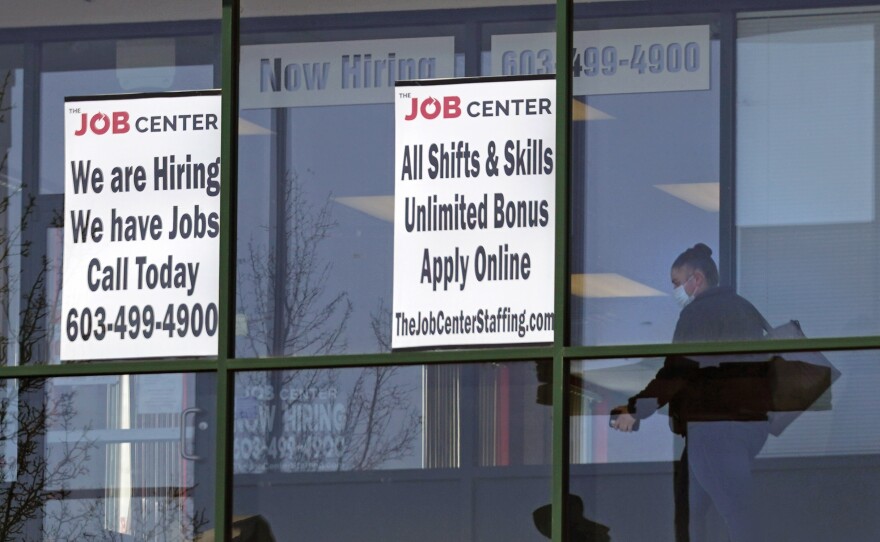 In this March 2, 2021, file photo, a woman, wearing a protective mask due to the coronavirus, walks past the signs of an employment agency, in Manchester, N.H. A new report finds that Latinas have left the workforce at rates higher than any other demographic and also have had some of the highest unemployment rates throughout the pandemic.
