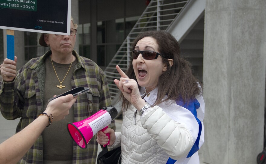 A person is interviewed at a protest for Gaza. They have the flag of Israel draped around their shoulders. UCSD in San Diego, Calif. March 6, 2024.