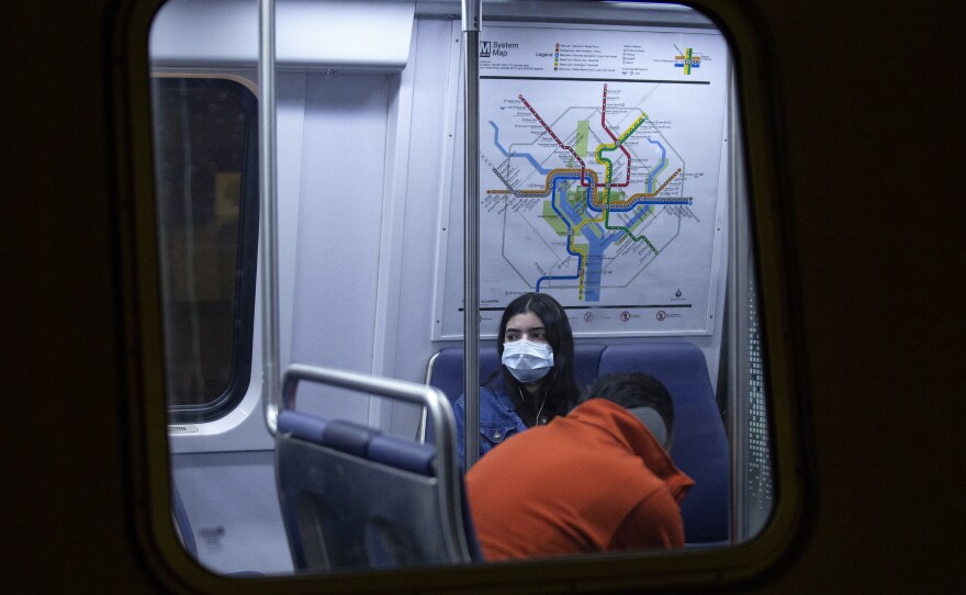 A commuter wearing a face mask rides a train stopped at the Gallery Place station in Washington, D.C.