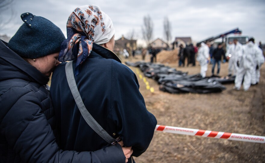 Women embrace each other as bodies are exhumed from a mass grave to be inspected for possible war crimes on April 8 in Bucha, outside Kyiv, Ukraine.