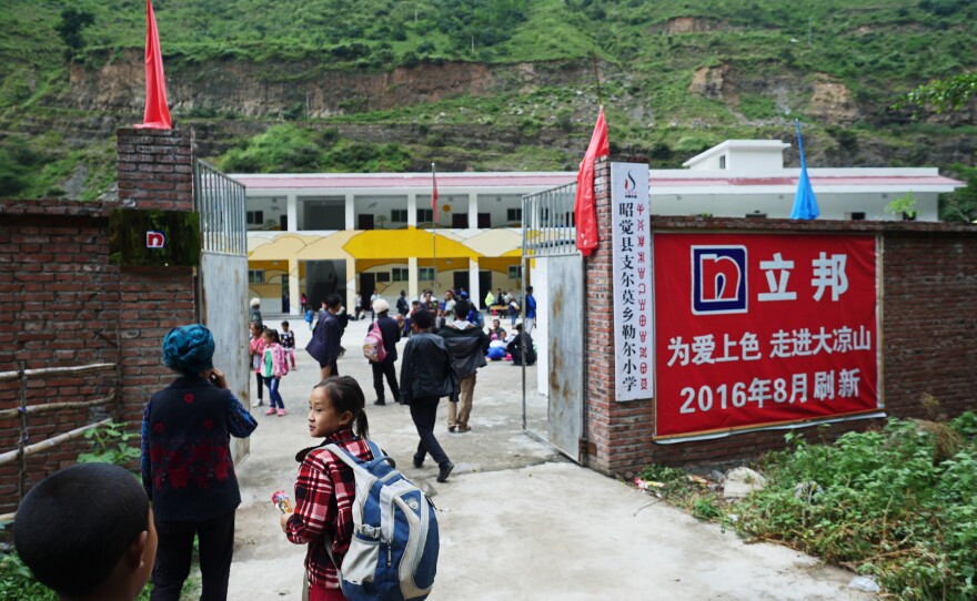Ethnic Yi schoolchildren arrive for the first day of a new semester at the Le'er primary school. Most of the children can only get to the school by making a perilous descent down a mountain from their homes in Atule'er village. The name of the school in Chinese (left) and the pictographic script of the Yi is on a sign at the school's entrance.
