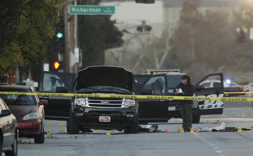 An investigator looks at a SUV that was involved in a police shootout with suspects, in San Bernardino on Thursday. At least 14 people are dead and 17 wounded after a shooting Wednesday morning in San Bernardino.