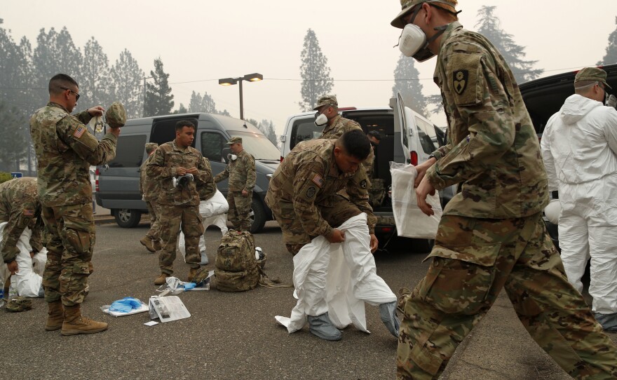 Members of the California Army National Guard put on protective suits before searching for victims of the Camp Fire in Paradise, Calif., on Wednesday.