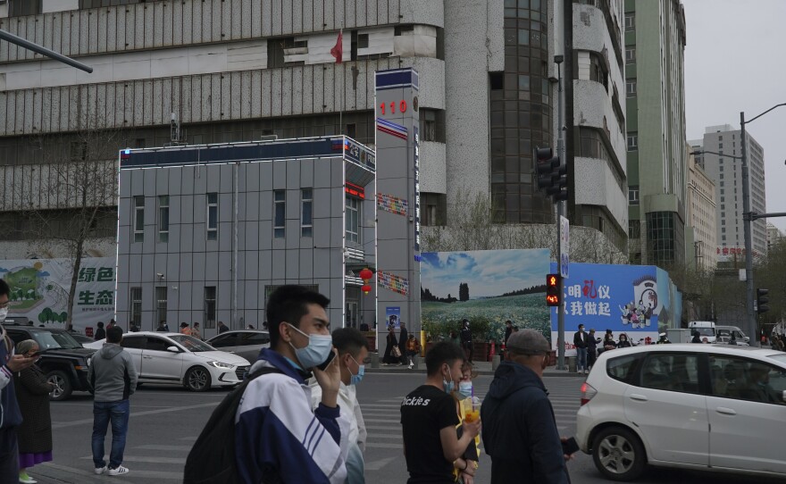 Pedestrians walk past a police station in Urumqi in April 2021. At least 1,300 state boarding schools are set up across Xinjiang.