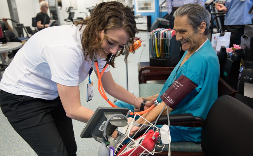 Exercise physiologist Courtney Conners checks Mario Oikonomides' vital signs before his cardiac rehab workout at the University of Virginia Health System clinic.