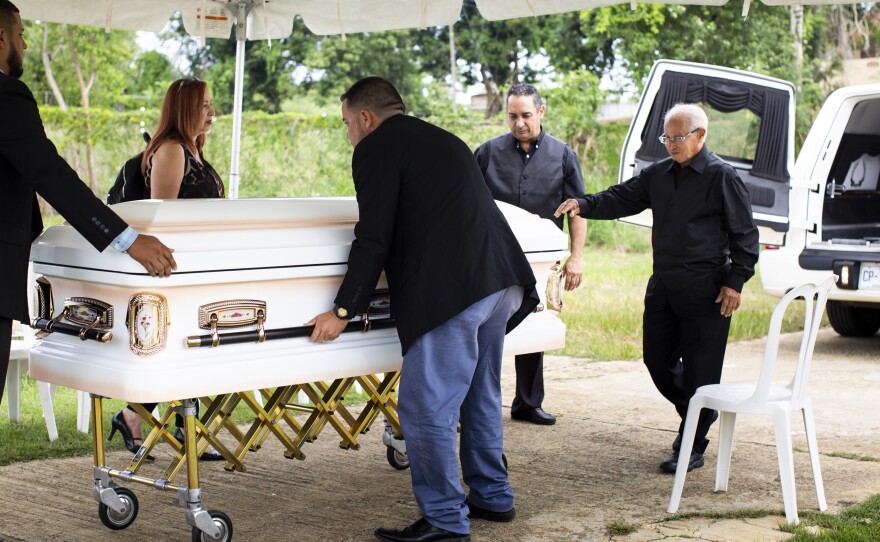 Armando Colón (second from right) helps lift his mother's casket out of the hearse at a cemetery 40 minutes away from Lares.