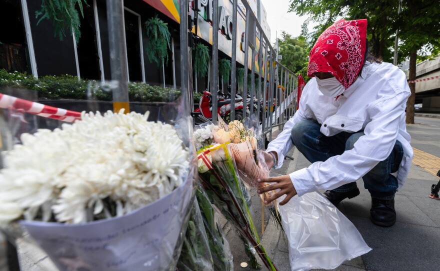 A man puts flowers outside the music bar where a fire killed a number of people in Bangkok, Thailand, Tuesday, July 14, 2026.