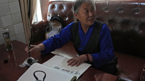 Kalsang Lhamo, a 73-year-old retired nurse, practices Tibetan calligraphy at the Chengguan District Day Care Center for the Elderly in western China's Tibet autonomous region on July 20, 2026, during a government-organized visit for foreign journalists.