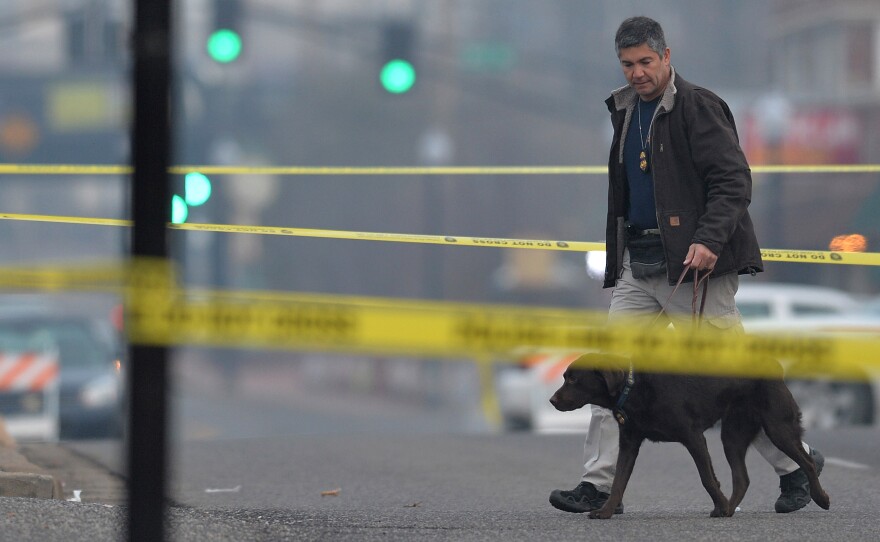 An agent with the Department of Alcohol Tobacco and Firearms arrives on the crime scene outside the Ferguson Police Department on Thursday. Just down the road, community leaders and residents have been struggling to digest this latest shock.