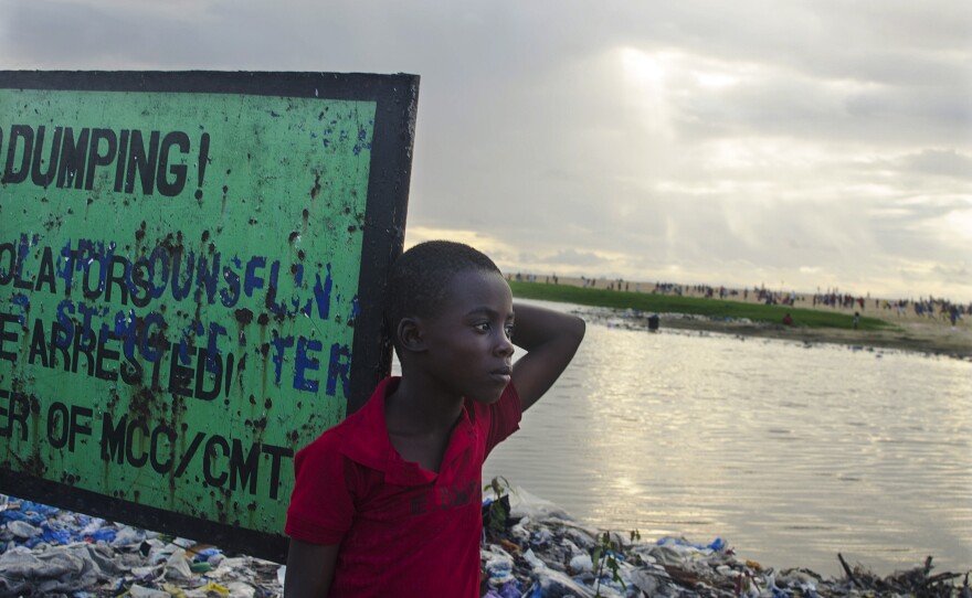 Prince, a West Point resident, stands by a garbage dump near a sign that says "No dumping."