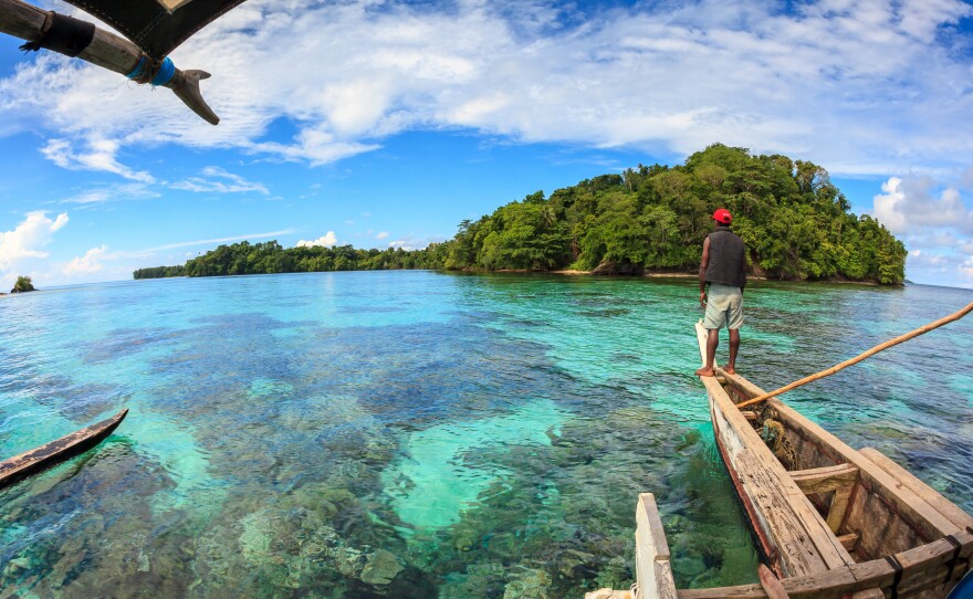 A fisherman surveys the shallow coral reef near a small island in Papua New Guinea. Some of the reefs around these islands are surprisingly healthy as a result of active fishery management by local people.