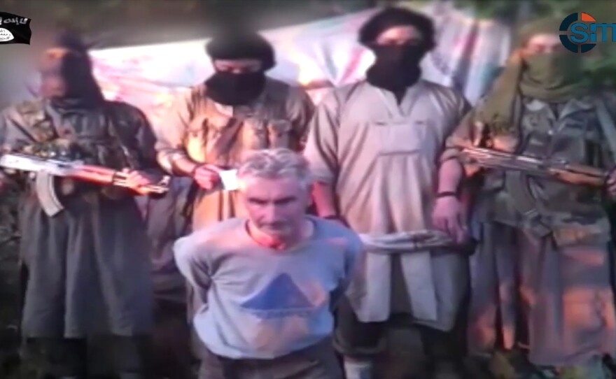In this still image from video published on the Internet on Wednesday, by a group calling itself Jund al-Khilafah, or Soldiers of the Caliphate, shows members of the group standing behind French mountaineer Herve Gourdel just before beheading him.