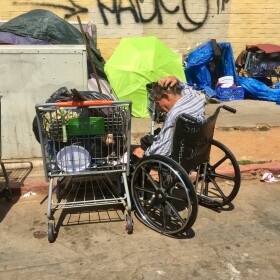 A man sits in a wheelchair near homeless encampments on 17th Street in San Diego's East Village, July 6, 2017.