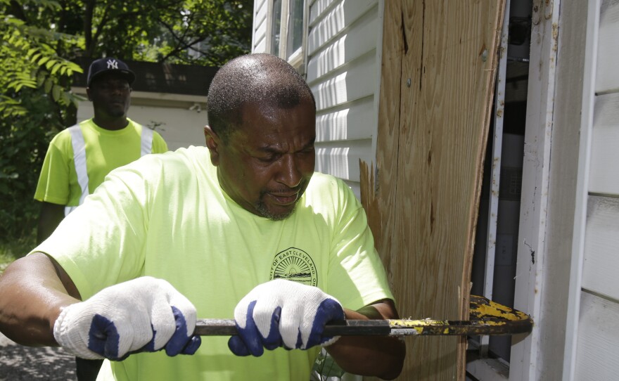 East Cleveland service department employee Ray Allen breaks into an abandoned house so searchers can enter on Sunday.