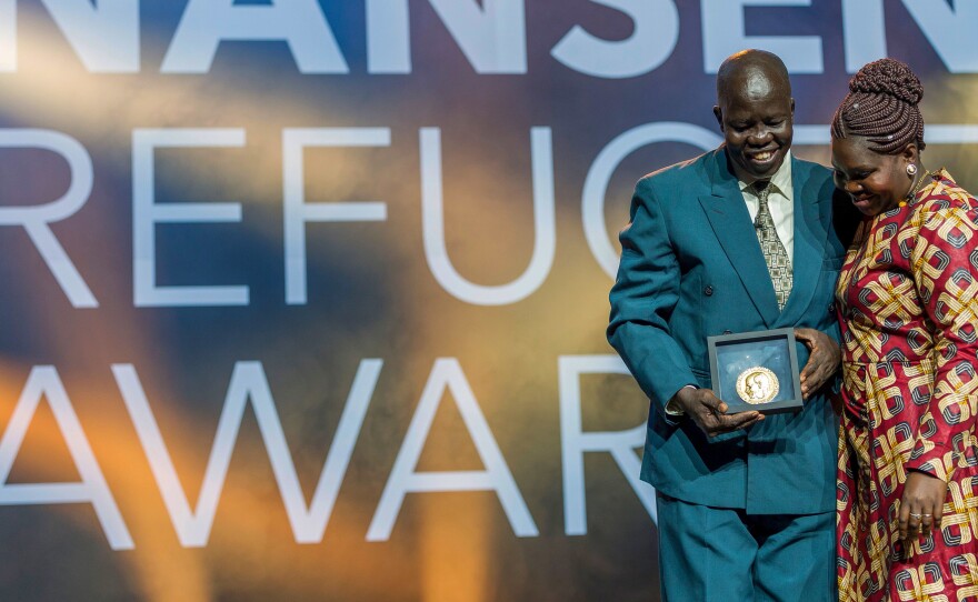 Evan Atar Adaha, surgeon and medical director at a hospital in South Sudan, accepts the U.N.'s Nansen Refugee Award in Geneva, on October 1. His wife, Angela Atar, is at right.