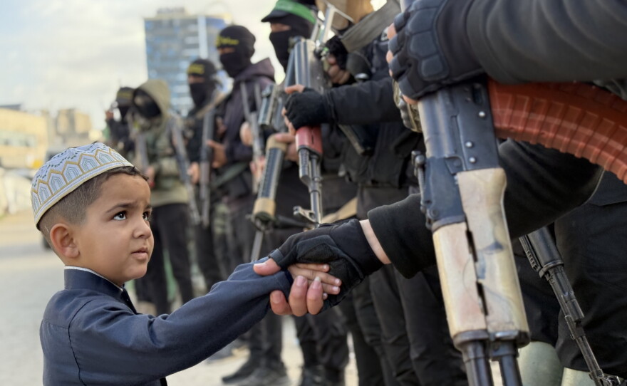A Palestinian boy shakes hands with Hamas militants on the first day of Eid al-Fitr, following the end of the Muslim holy month of Ramadan, in Gaza City on March 20, 2026.