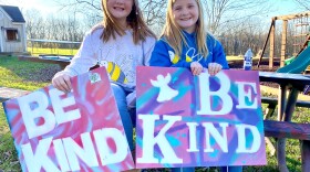 On a November afternoon sisters Raegan and Rylyn Richins sit at their picnic table in their backyard in a Kentucky county holding signs they just painted.