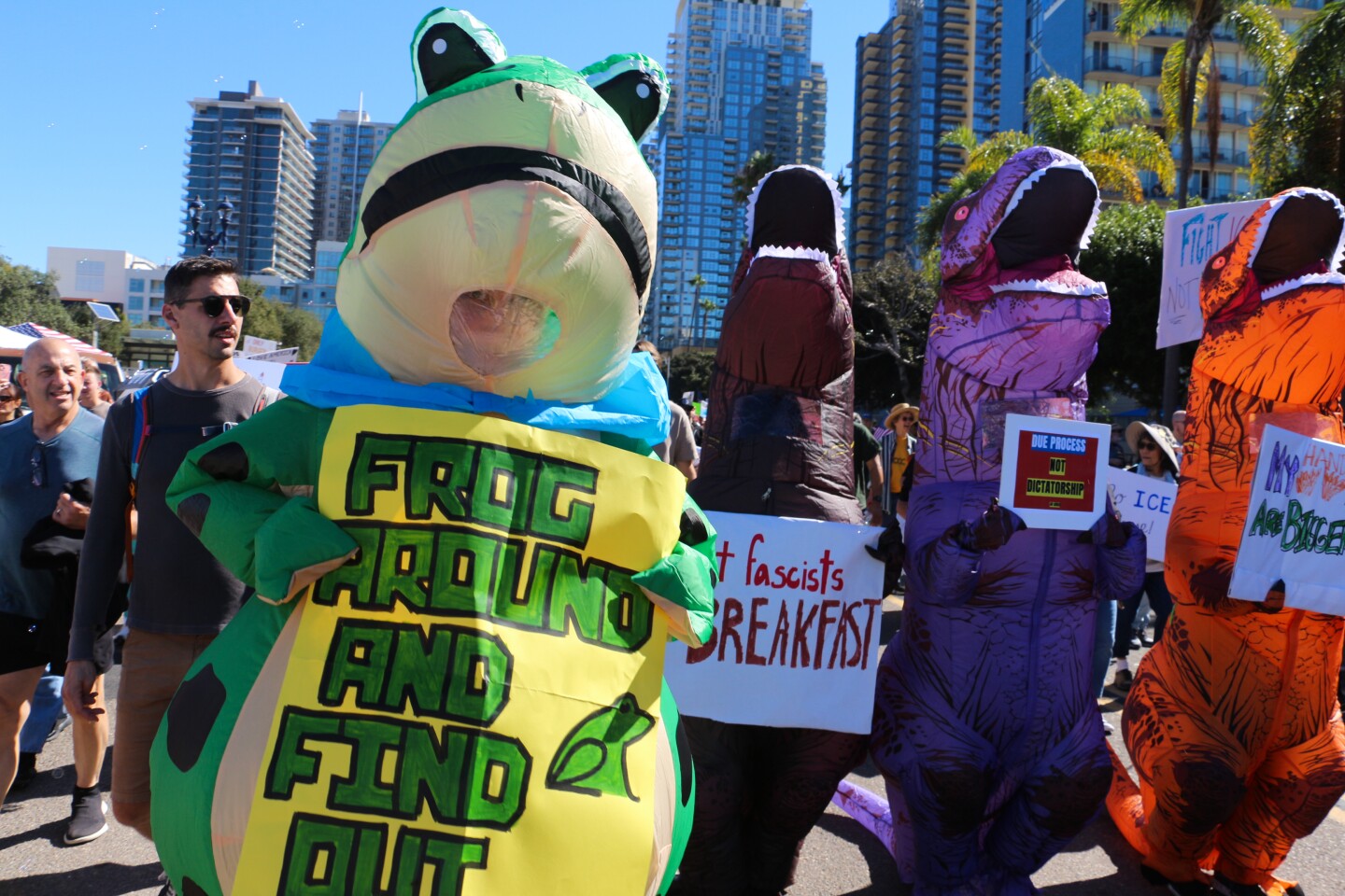 Costumed protestors hold up signs during the "No Kings" protest in downtown San Diego on Oct. 18, 2025.