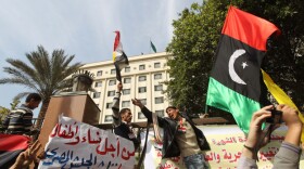 Protesters shout slogans against Libyan leader Moamer Kadhafi as they hold up the old Libya flag during a demonstration Tuesday outside the Arab League headquarters in Cairo.
