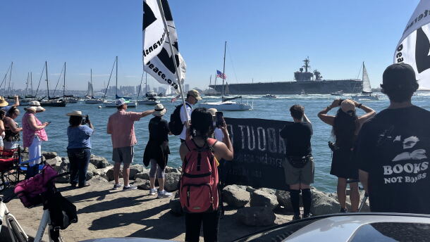 Supporters and protestors gather with signage along Shelter Island's shoreline for the USS Lincoln's arrival, Oct. 8, 2026.