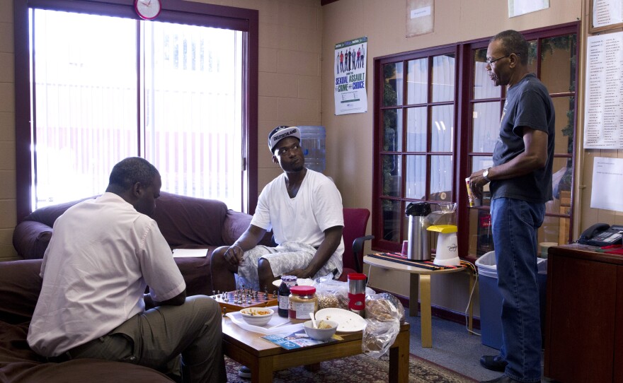 David Lee Robinson Jr., a volunteer facilitator (left), plays chess with Michael Ward at a prison reentry program site, while Felton Howard, a navigator with the program, looks on. Ward spent more than eight years in the state prison system before his release in 2012.