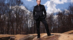 Promotional photo of Clay Aiken standing outdoors, dressed in a black suit. Chart-topping “American Idol” vocalist Clay Aiken brings his clarion voice and personal interpretations to new arrangements of iconic songs.