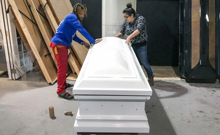 Kenneth Burnett and Maggie Rivera sand a casket, readying it for a pink camouflage paint job at the shop in Edna, Texas. The woman it is for loved to hunt.