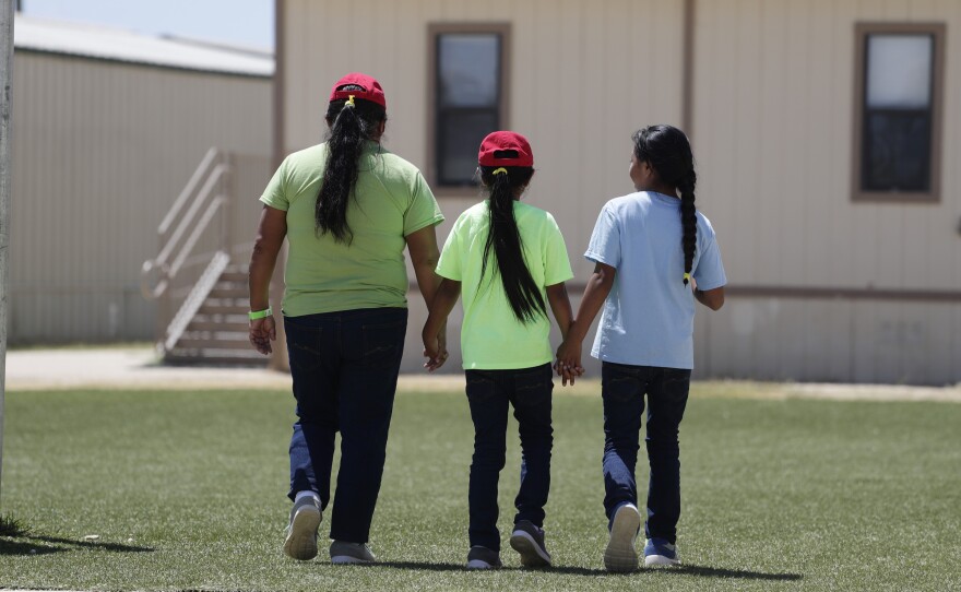 Immigrants seeking asylum hold hands as they leave a cafeteria at the ICE South Texas Family Residential Center. Independent inspectors told the judge that COVID-19 tests at the centers and the infection rates in the counties where the Texas facilities are located are cause for concern.